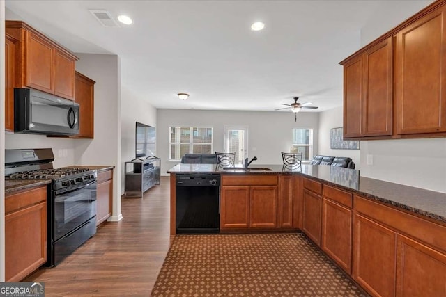 kitchen featuring dark wood-type flooring, sink, kitchen peninsula, ceiling fan, and black appliances