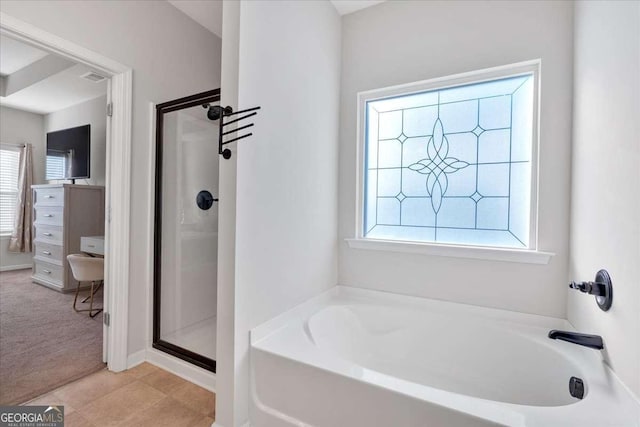 bathroom featuring a wealth of natural light and shower with separate bathtub