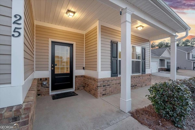 exterior entry at dusk featuring a garage and covered porch