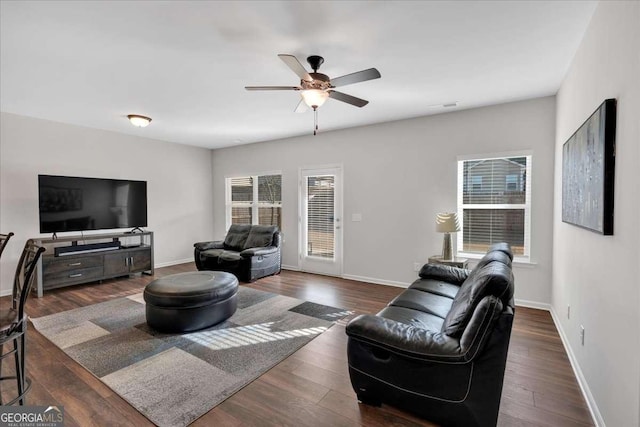 living room featuring dark wood-type flooring and ceiling fan