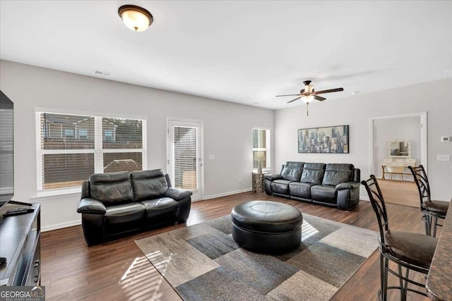 living room featuring dark wood-type flooring and ceiling fan