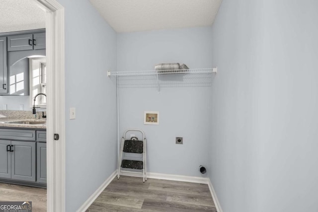 laundry room with sink, hardwood / wood-style flooring, washer hookup, electric dryer hookup, and a textured ceiling