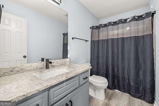 bathroom featuring walk in shower, toilet, a textured ceiling, vanity, and hardwood / wood-style floors