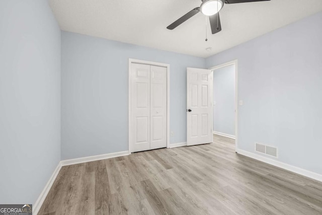 unfurnished bedroom with ceiling fan, a closet, and light wood-type flooring