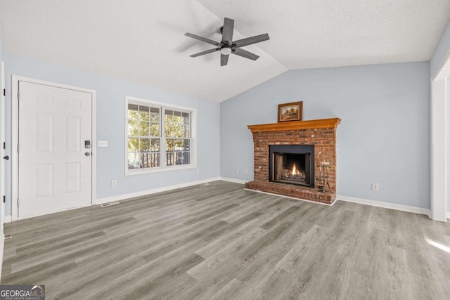 unfurnished living room with a fireplace, vaulted ceiling, light hardwood / wood-style flooring, and a textured ceiling