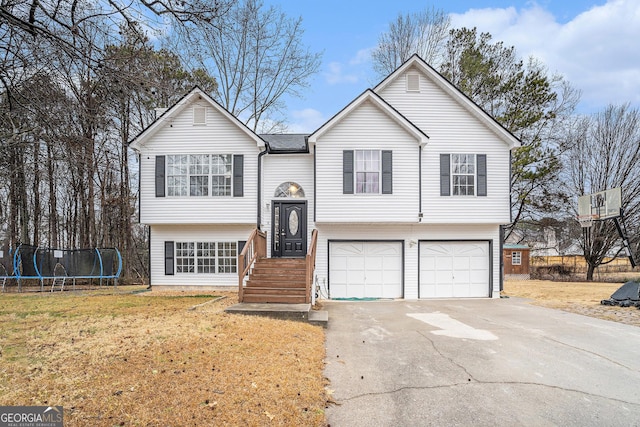 bi-level home with a trampoline, a garage, and a front lawn