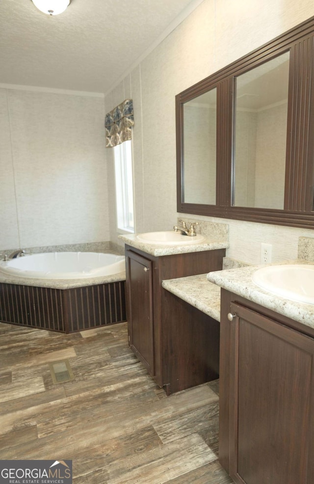 bathroom featuring vanity, hardwood / wood-style floors, ornamental molding, and a bathing tub