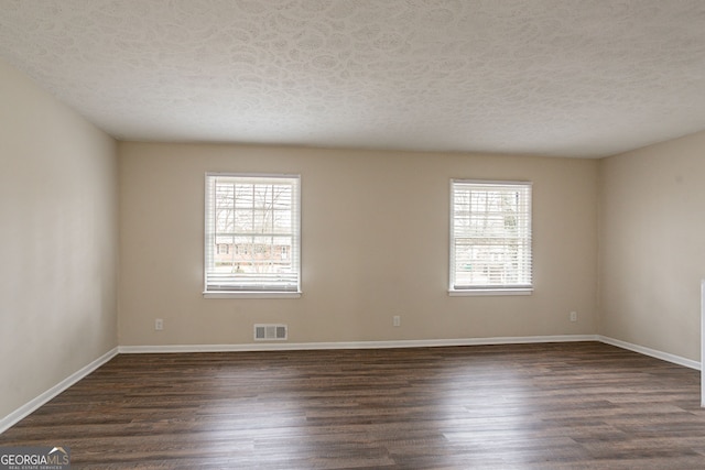 unfurnished room with dark hardwood / wood-style floors and a textured ceiling