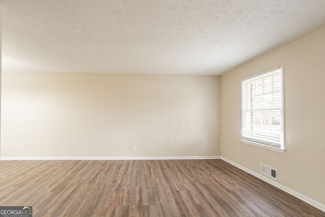 spare room with dark hardwood / wood-style flooring and a textured ceiling