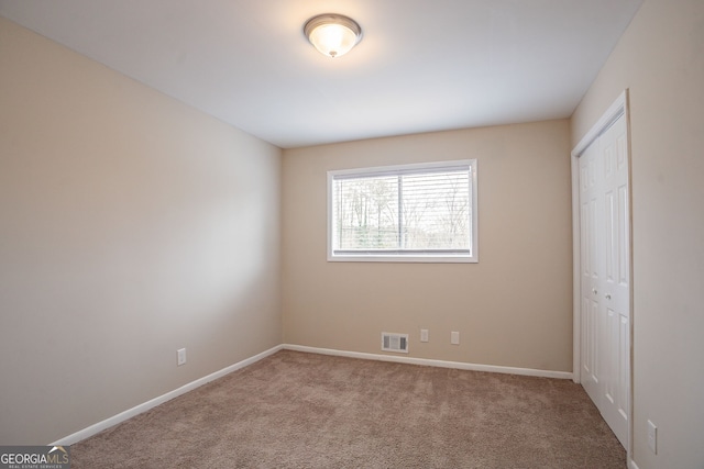 unfurnished bedroom with light colored carpet and a closet