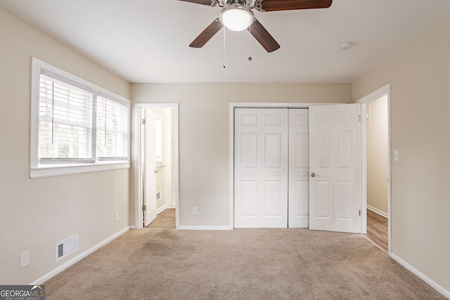 unfurnished bedroom featuring ensuite bathroom, light colored carpet, ceiling fan, and a closet