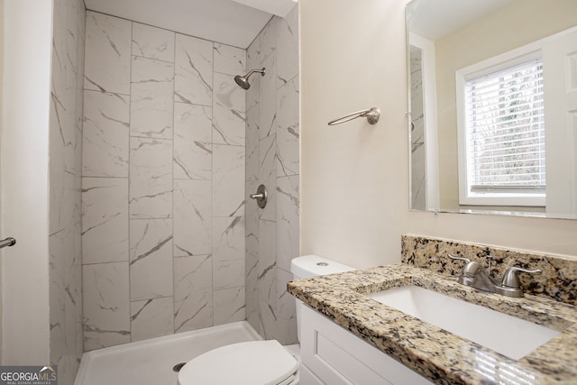 bathroom featuring a tile shower, vanity, and toilet