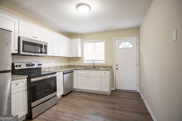 kitchen with light stone countertops, appliances with stainless steel finishes, sink, and white cabinets