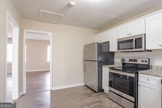 kitchen with white cabinetry, light hardwood / wood-style flooring, light stone countertops, and appliances with stainless steel finishes