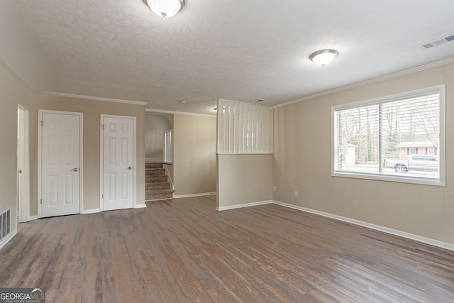 spare room with crown molding, dark hardwood / wood-style floors, and a textured ceiling