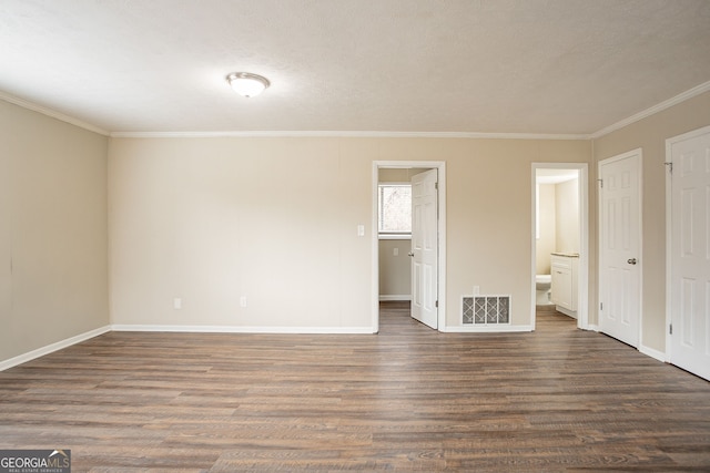 unfurnished bedroom with dark wood-type flooring, ornamental molding, a textured ceiling, and ensuite bathroom