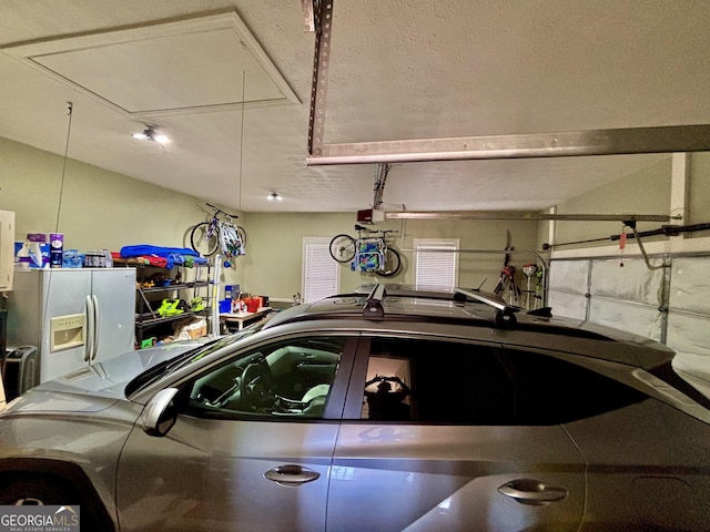 garage featuring a garage door opener and white fridge with ice dispenser