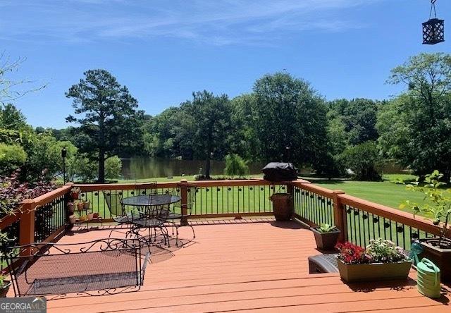 wooden terrace featuring a lawn and a water view