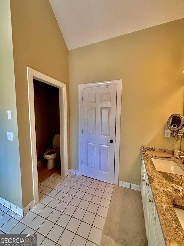 bathroom featuring vanity, lofted ceiling, tile patterned floors, and toilet