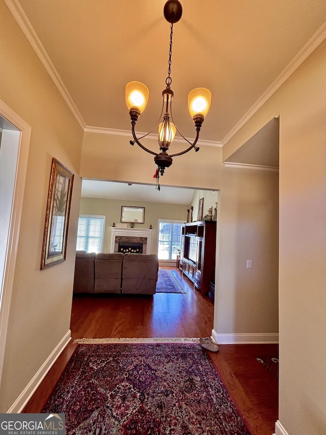 hallway featuring an inviting chandelier, ornamental molding, and dark hardwood / wood-style floors