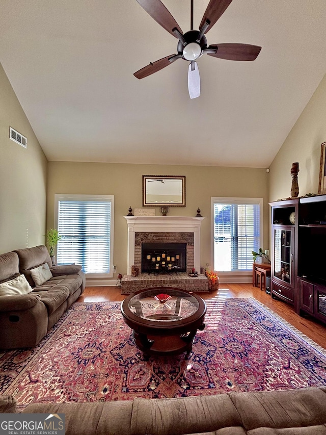 living room featuring ceiling fan, vaulted ceiling, a premium fireplace, and wood-type flooring