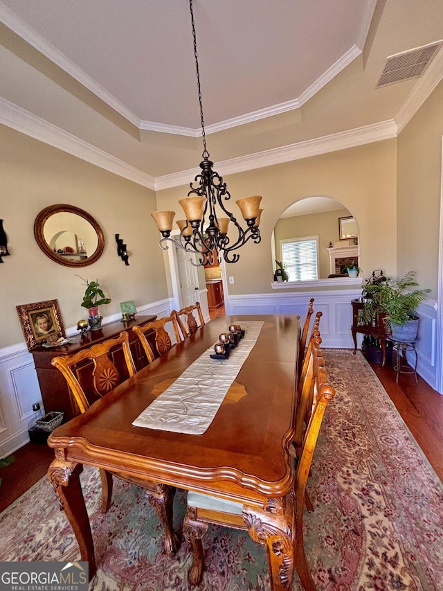 dining area featuring a notable chandelier, a tray ceiling, ornamental molding, and dark hardwood / wood-style floors