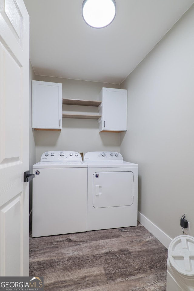 clothes washing area with cabinets, separate washer and dryer, and dark hardwood / wood-style floors