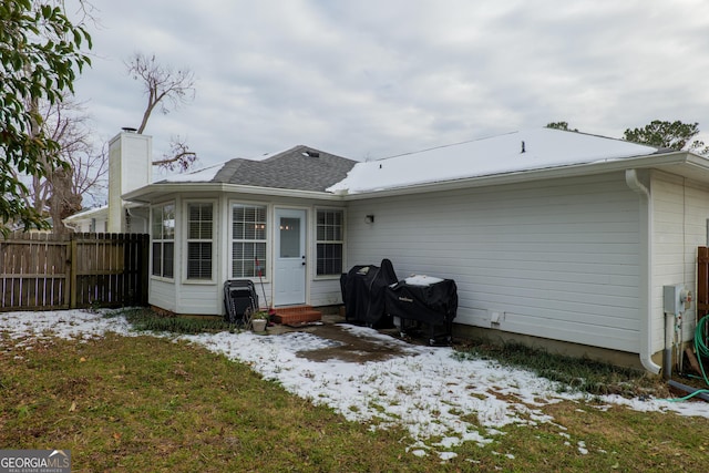 snow covered back of property featuring a lawn