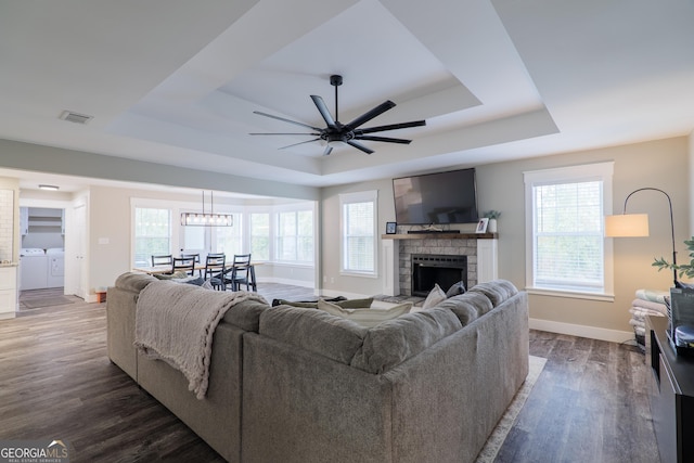 living room with washing machine and dryer, a healthy amount of sunlight, dark hardwood / wood-style flooring, and a tray ceiling