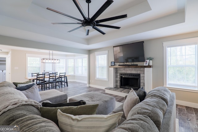 living room with hardwood / wood-style flooring, a stone fireplace, independent washer and dryer, and a tray ceiling