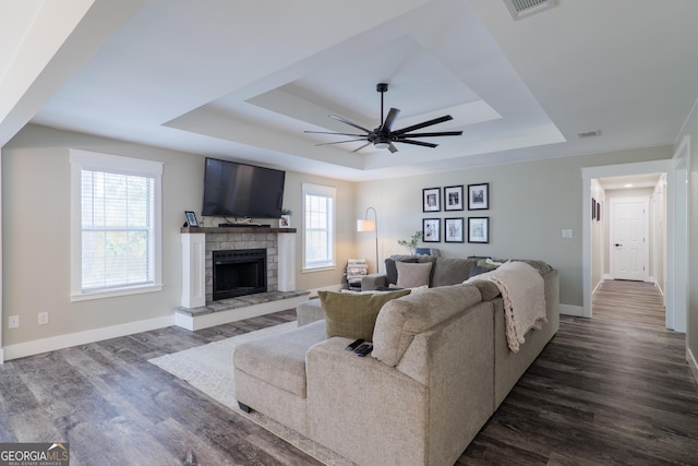 living room featuring plenty of natural light, a tray ceiling, and dark hardwood / wood-style flooring