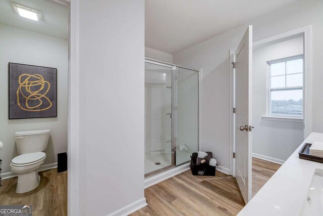 bathroom with vanity, hardwood / wood-style floors, a shower with door, and toilet