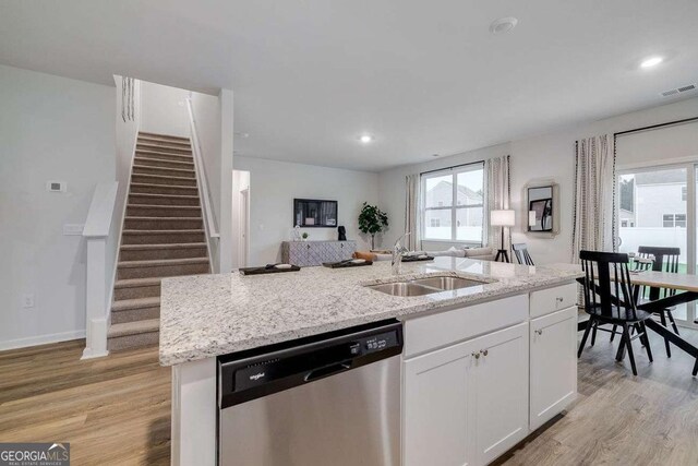 kitchen featuring sink, white cabinetry, stainless steel dishwasher, an island with sink, and light hardwood / wood-style floors