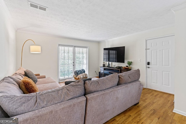 living room with crown molding, a textured ceiling, and light wood-type flooring