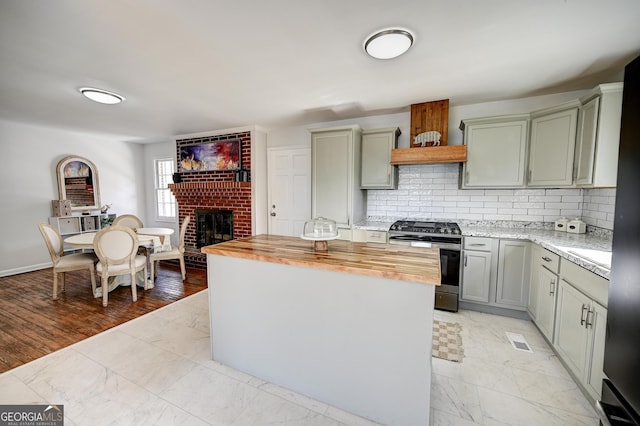 1202 Franklin Rd SW, Plainville, GA 30733 - kitchen featuring stainless steel gas range oven, butcher block countertops, light marble finish floors, and a fireplace