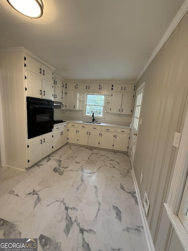 kitchen with sink, black oven, gas cooktop, ornamental molding, and white cabinets