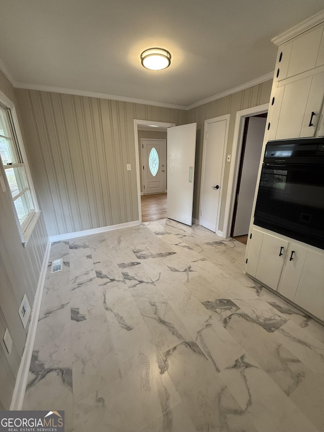 kitchen featuring white cabinets, ornamental molding, oven, and a wealth of natural light