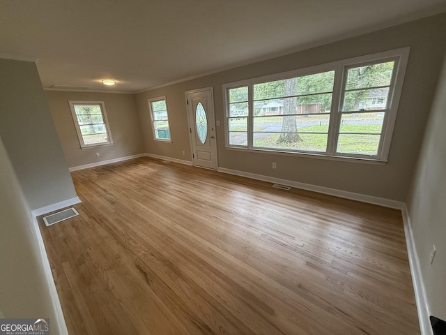 entrance foyer with ornamental molding and light hardwood / wood-style flooring