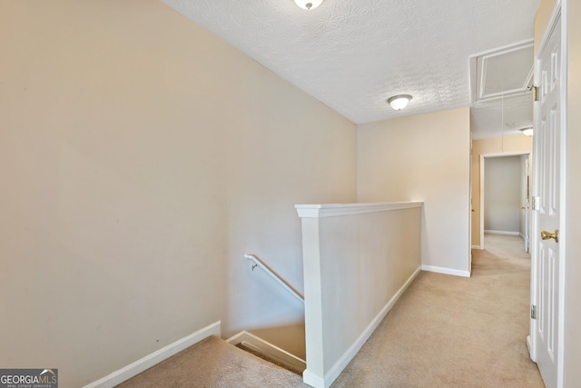 hall with light colored carpet and a textured ceiling