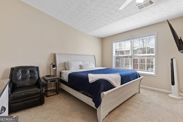 bedroom with ceiling fan, light carpet, and a textured ceiling