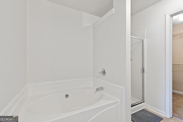 bathroom with tile patterned floors, a textured ceiling, and separate shower and tub