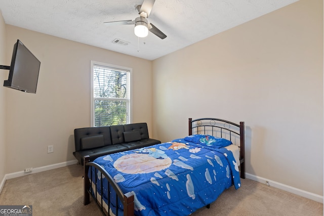 bedroom featuring ceiling fan, light carpet, and a textured ceiling