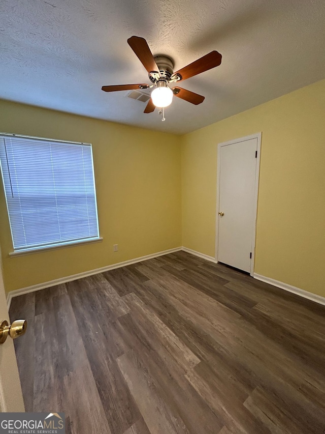 spare room featuring ceiling fan, dark wood-type flooring, and a textured ceiling