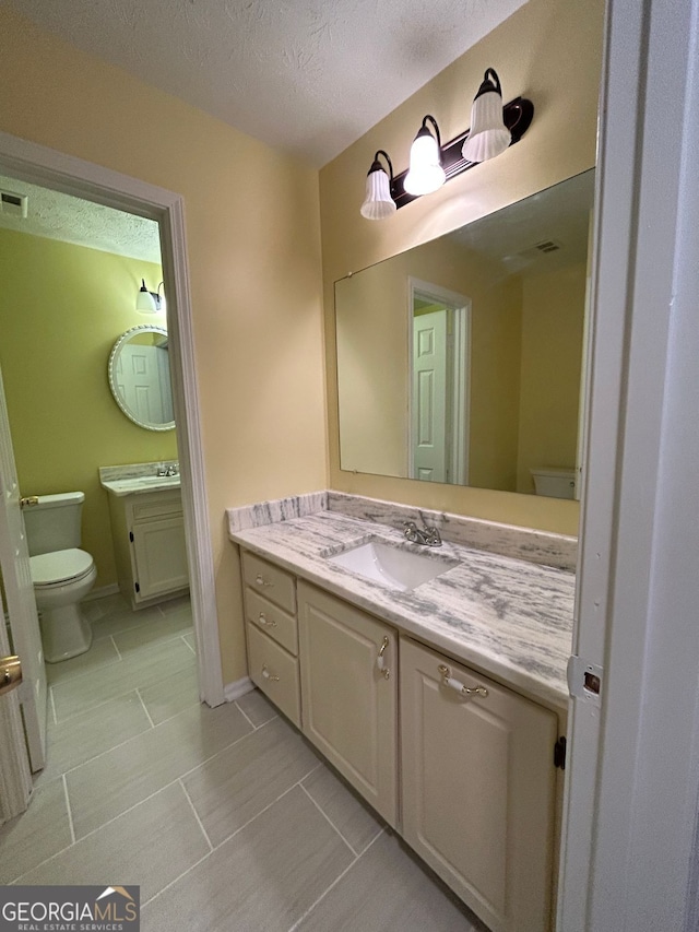 bathroom featuring tile patterned floors, vanity, toilet, and a textured ceiling