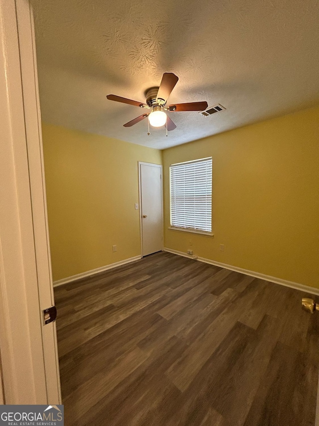 empty room featuring dark hardwood / wood-style flooring, ceiling fan, and a textured ceiling