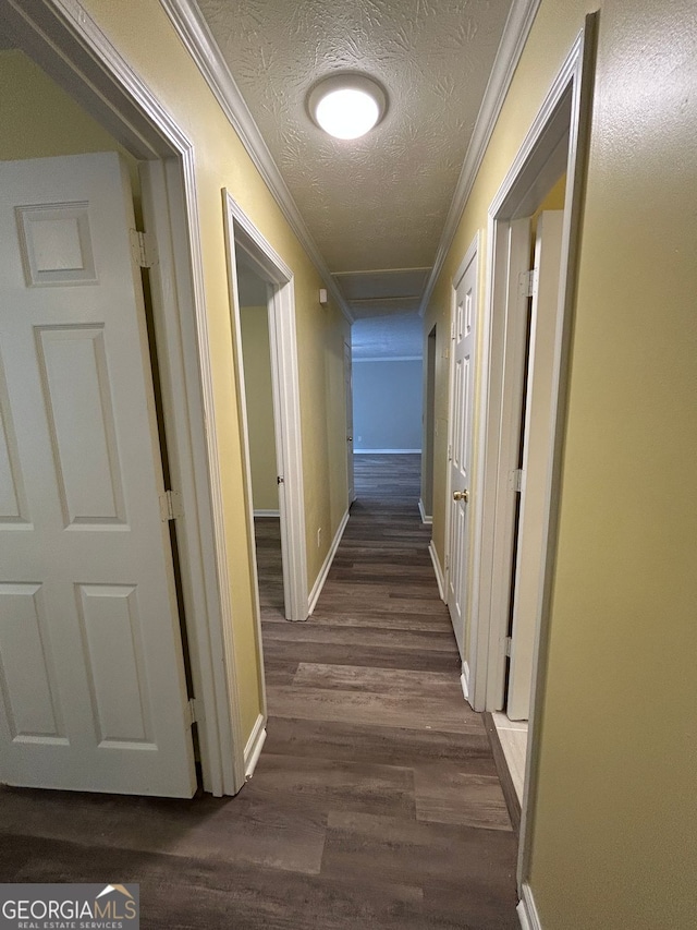 hallway with crown molding, dark wood-type flooring, and a textured ceiling