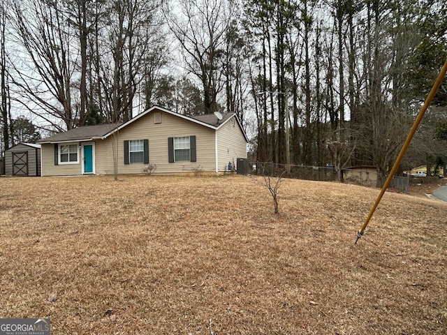 exterior space with central AC, a storage unit, and a lawn