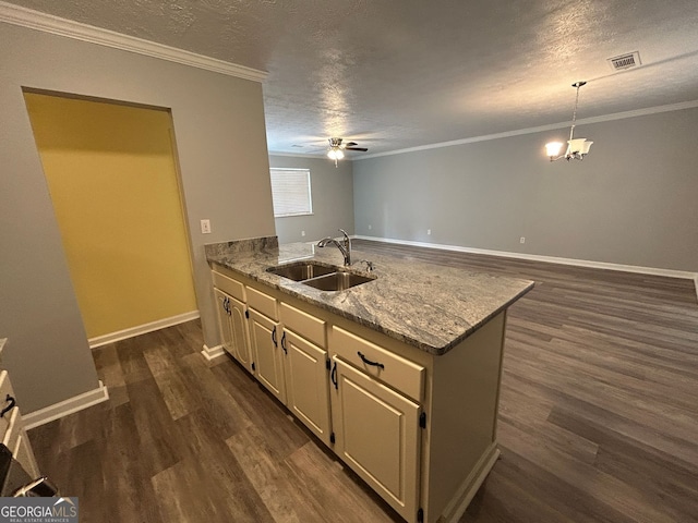 kitchen featuring pendant lighting, sink, ornamental molding, and a textured ceiling