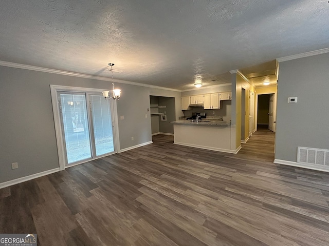 unfurnished living room with dark wood-type flooring, crown molding, and a notable chandelier