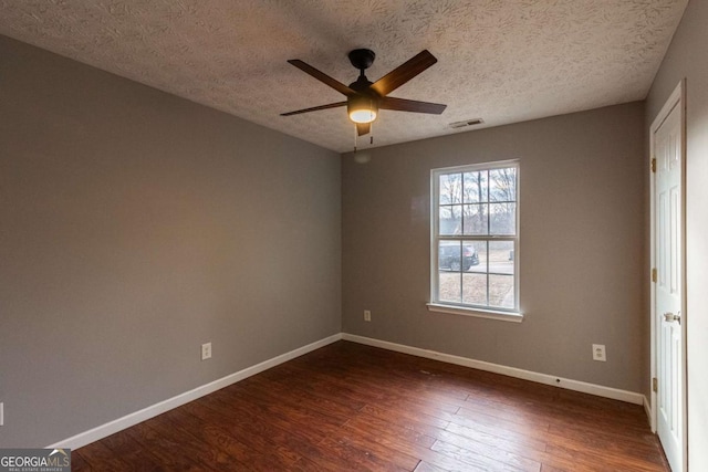 empty room featuring visible vents, dark wood finished floors, a ceiling fan, and baseboards